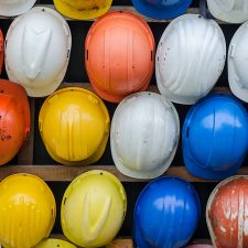 A variety of different hard hats that environmental consultants wear lined up in multiple rows