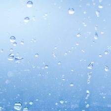 beads of water on PFAS treated glass in front of blue background