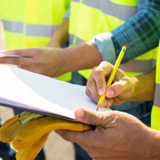 Environmental consultants in safety vests conducting real estate due diligence with clipboard